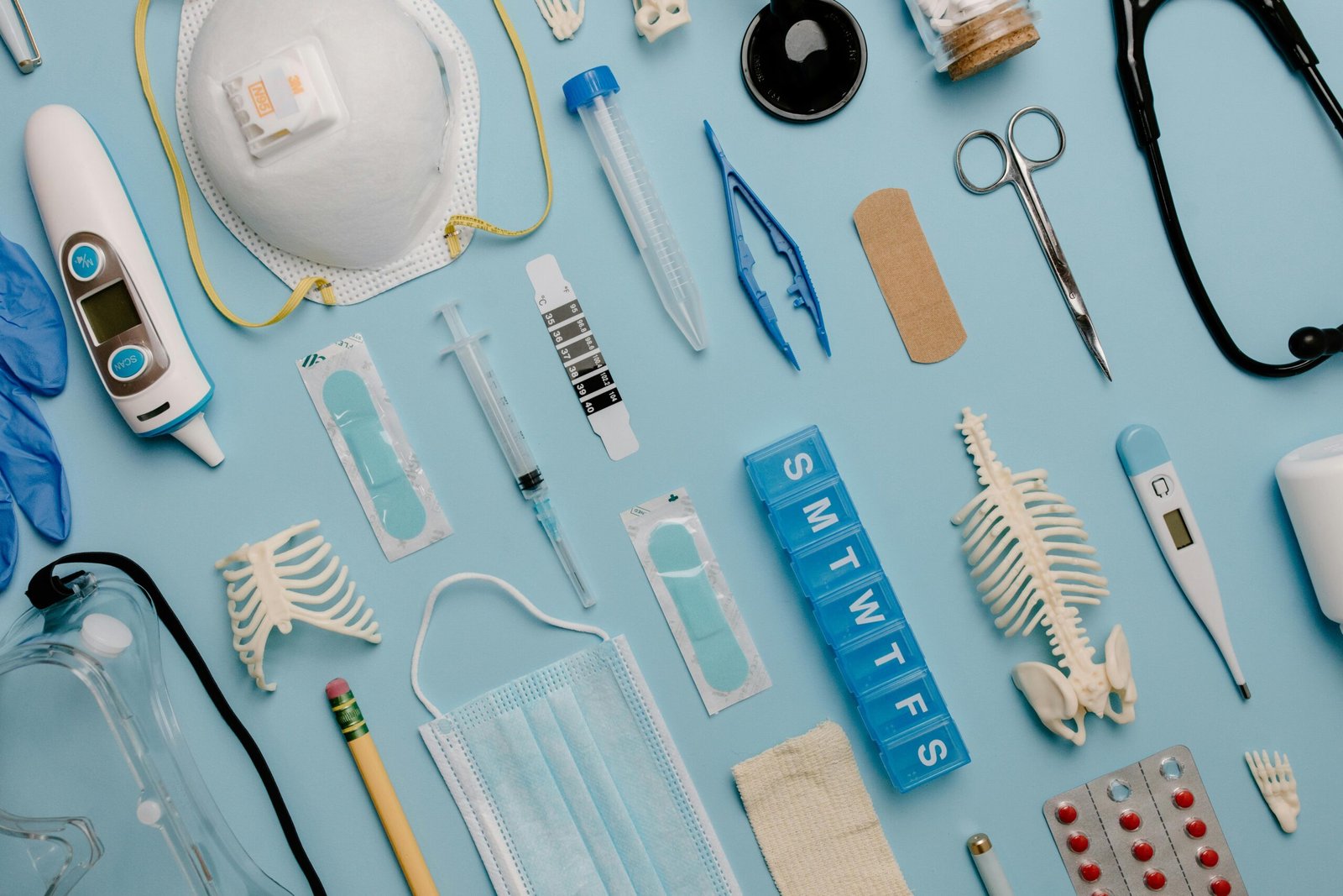 A comprehensive flat lay of diverse medical supplies including PPE and diagnostic equipment on a blue surface.