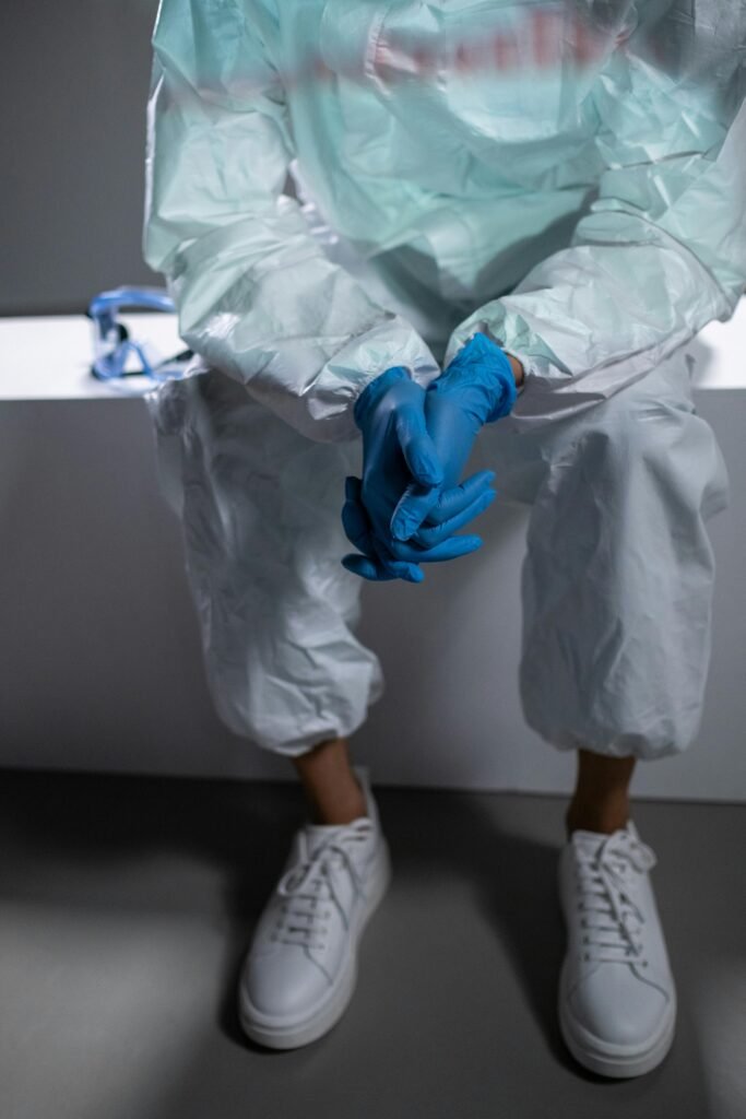 Close-up of a healthcare worker in protective gloves and suit sitting.